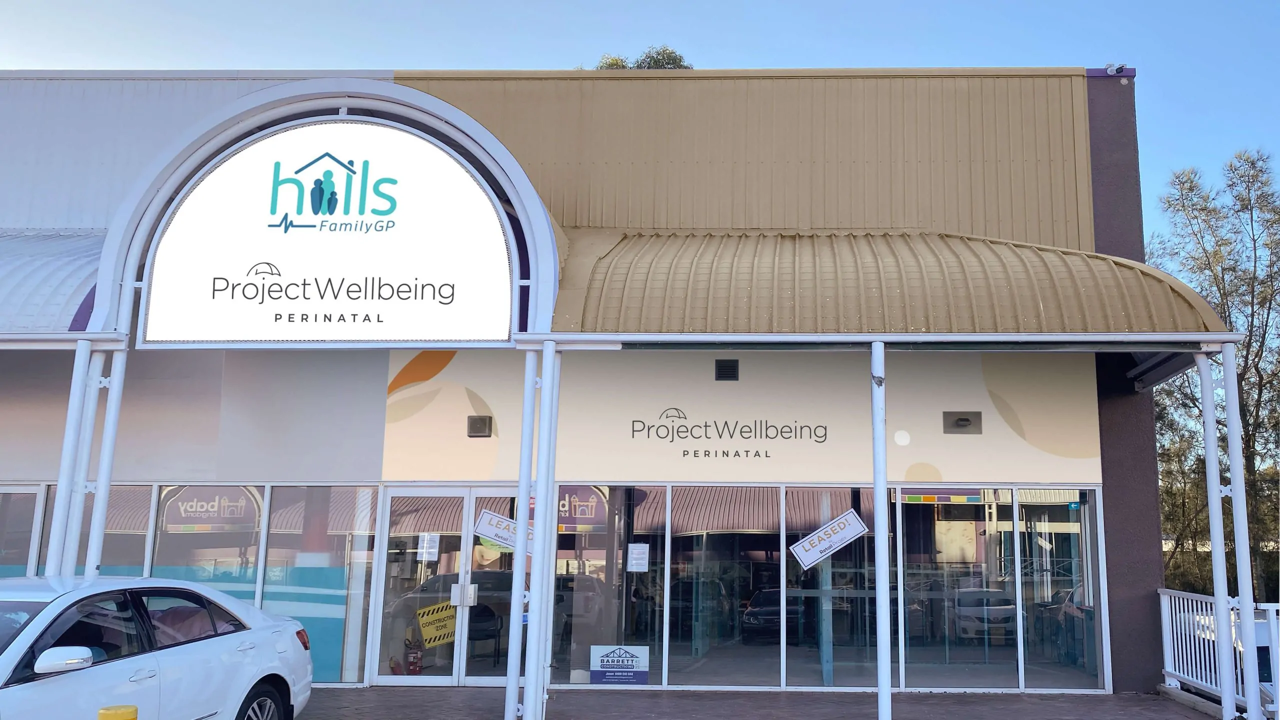 Exterior of Project Wellbeing Perinatal clinic with logo and glass front entrance.