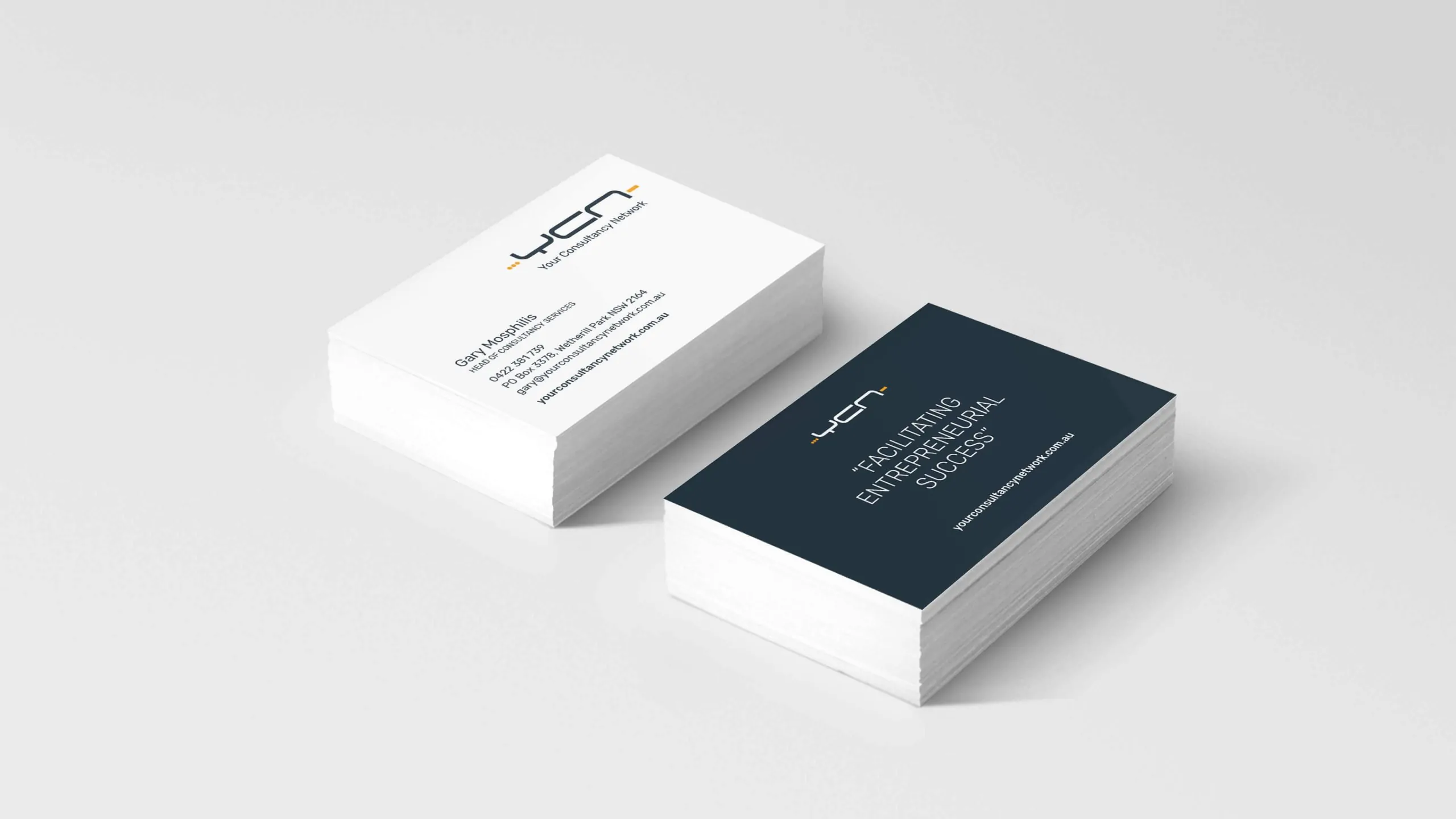 Stacked YCN business cards with logo, contact info, and tagline on dark navy side.