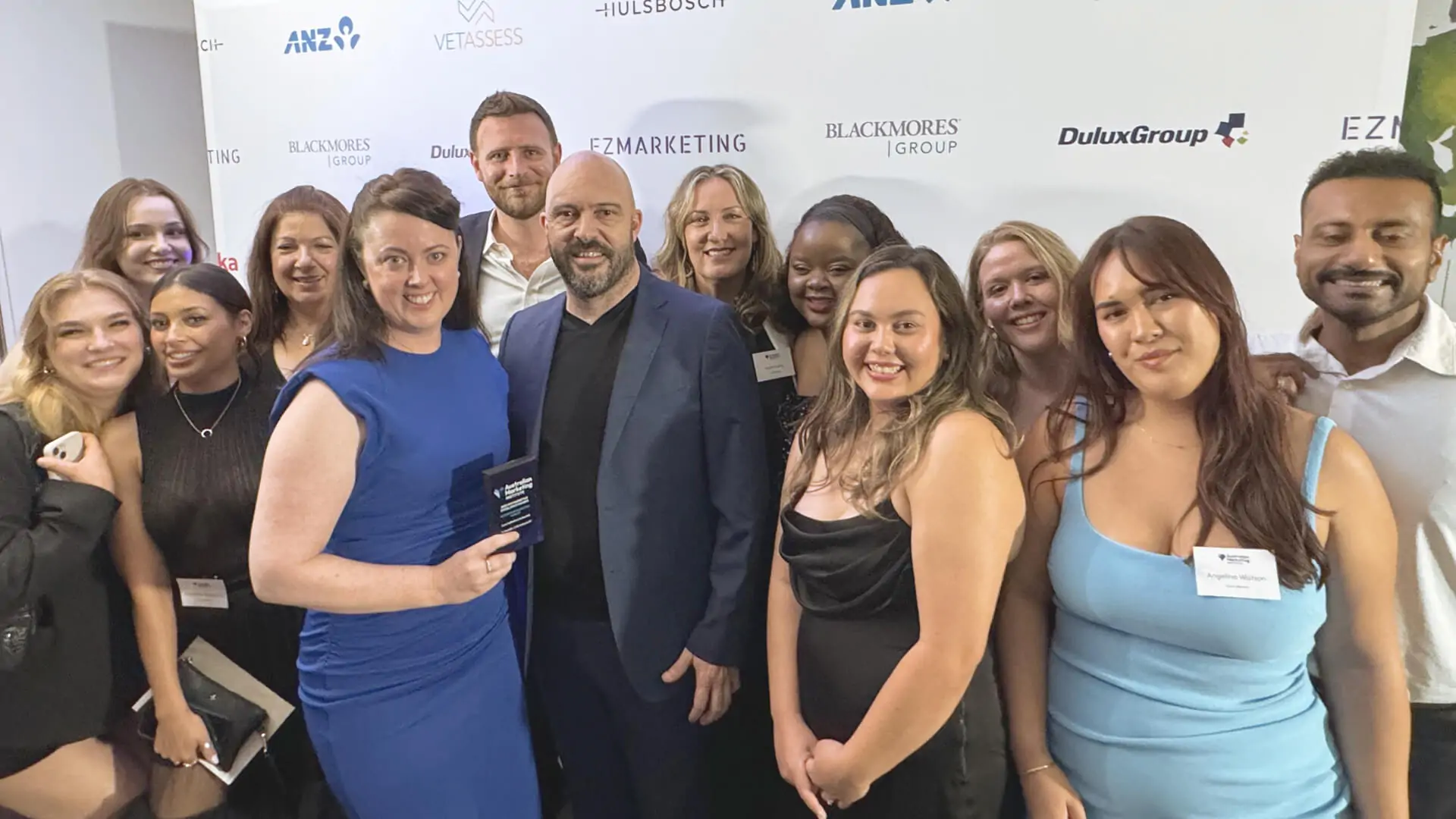 Group photo of a team celebrating with an award at a formal event.